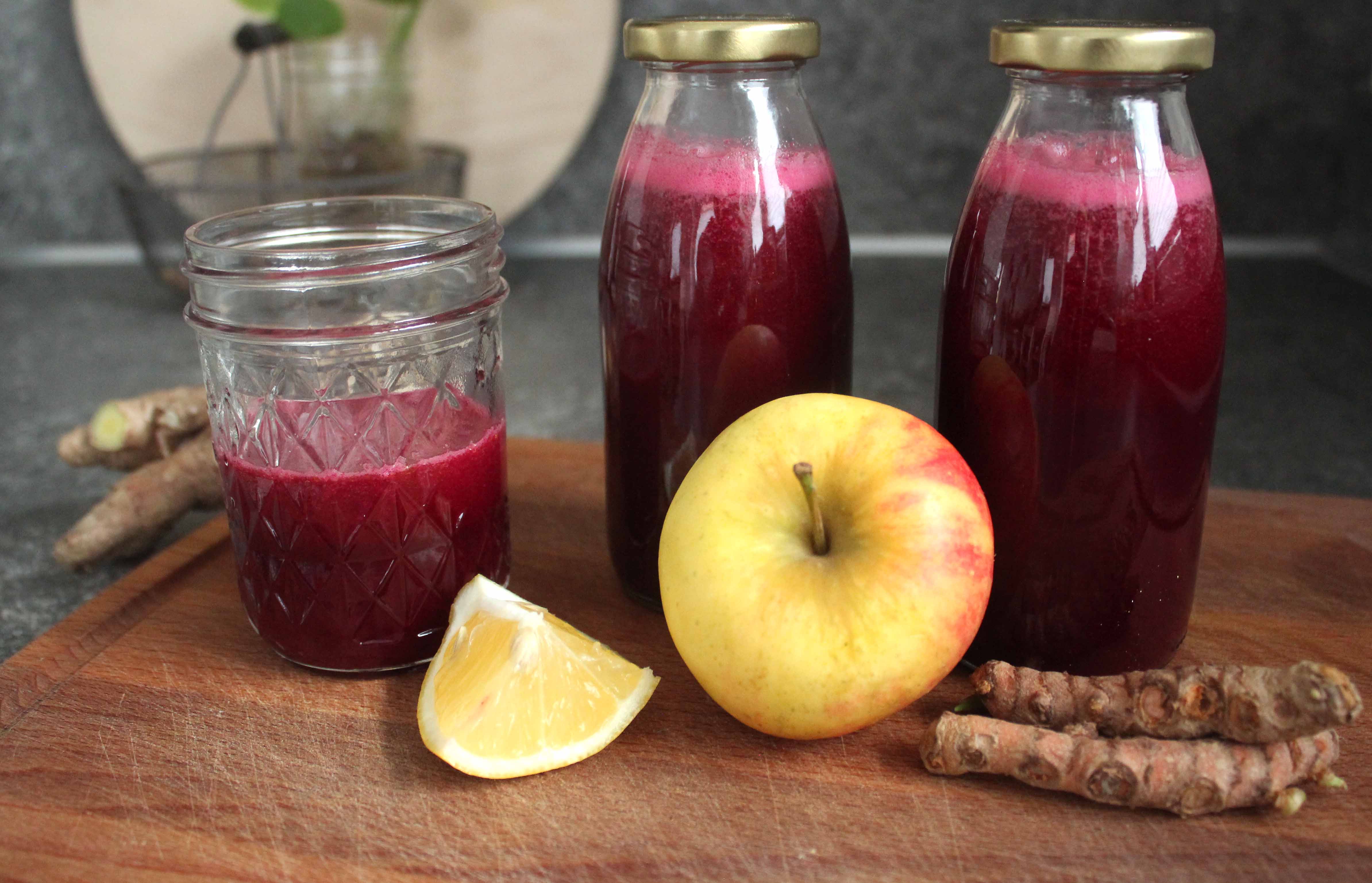 zwei Flaschen und ein Glas Rote Beete Saft mit Zutaten