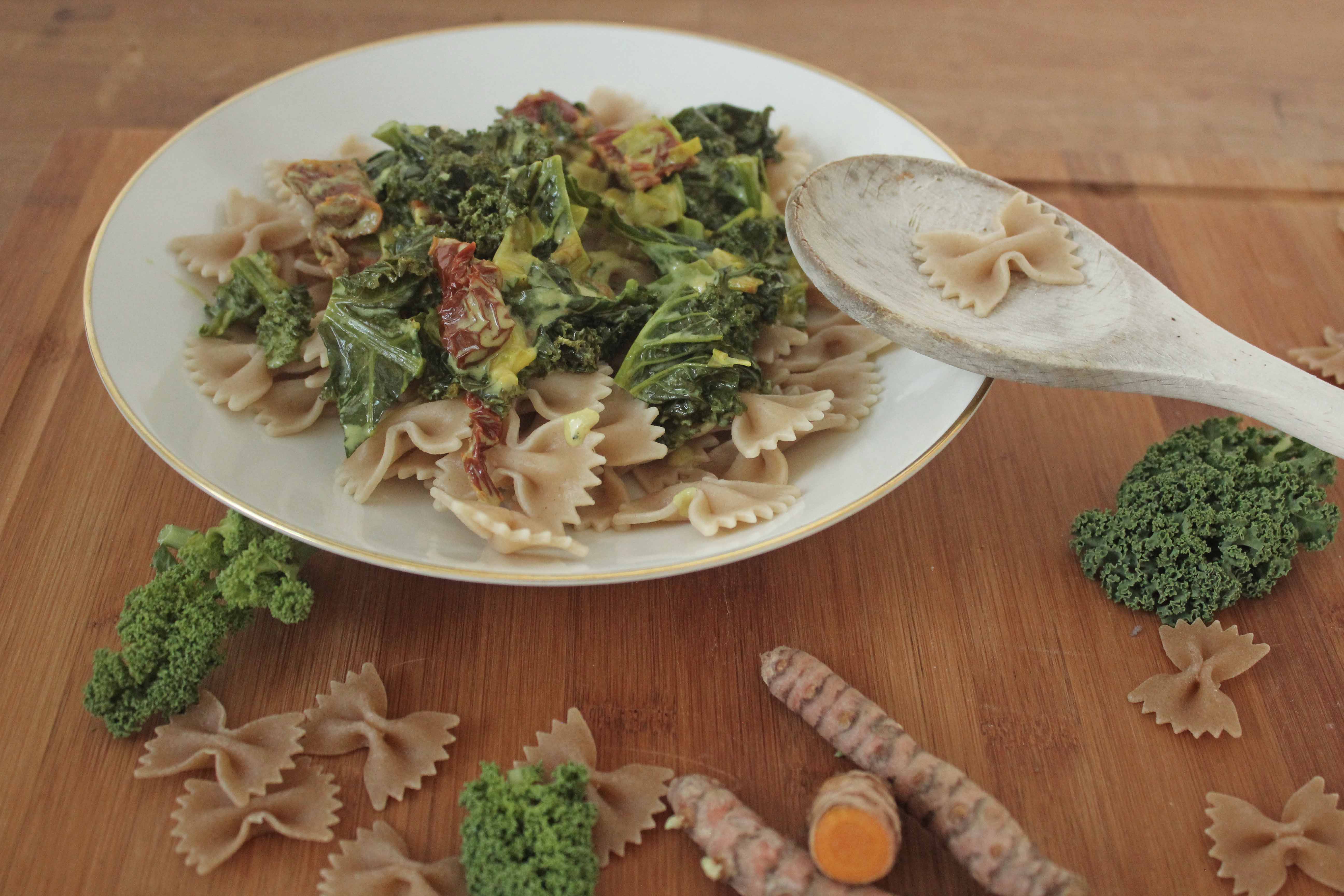 Teller mit Grünkohl-Tomaten-Pasta und rohen Zutaten