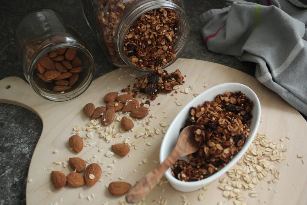 Granola in einem Schälchen mit Mandeln u Haferfocken drumherum
Umgekipptes Glas mit Granola